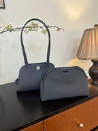 Blue top-handle handbag with matching small pouch at front on tabletop