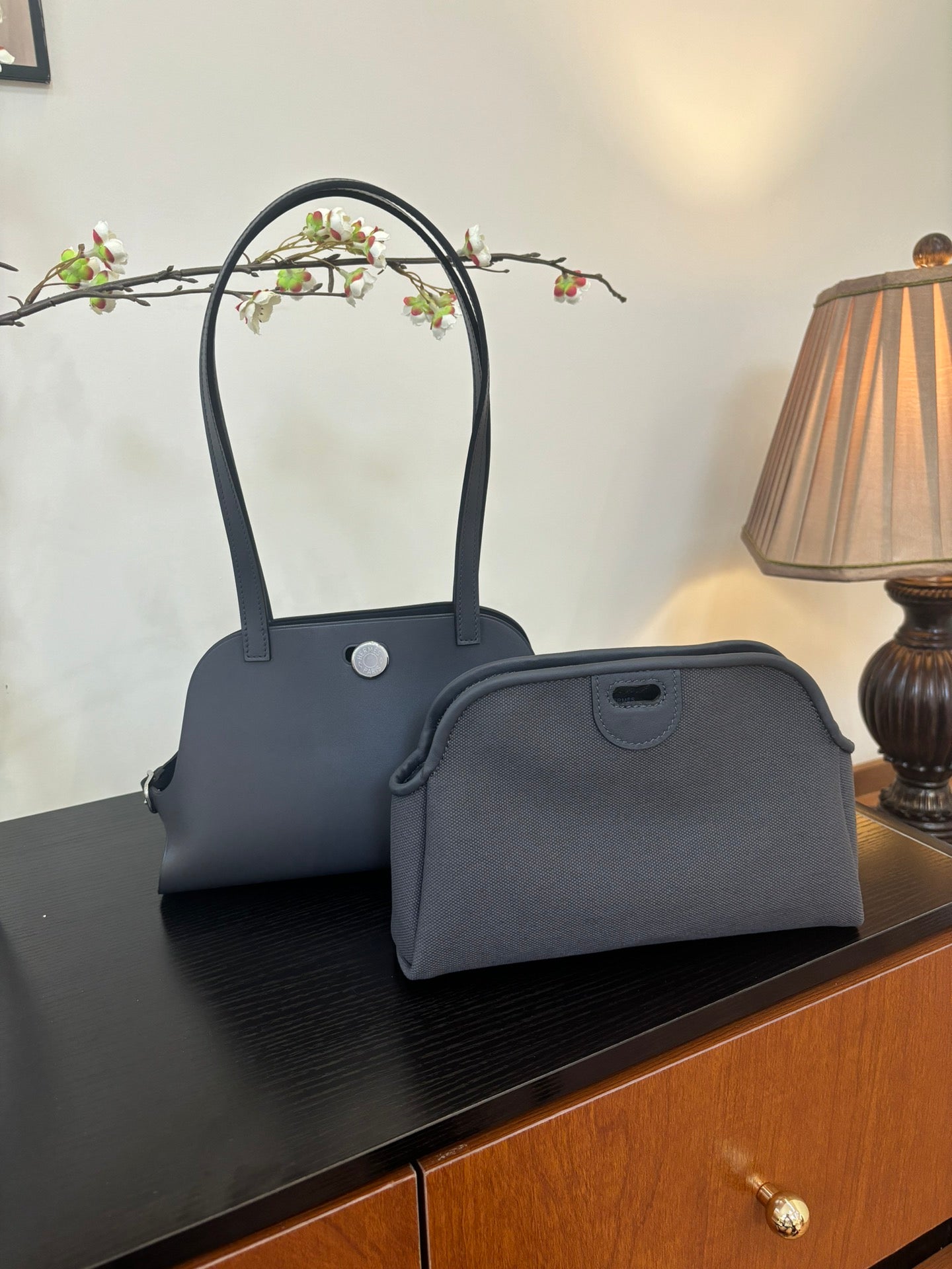 Blue top-handle handbag with matching small pouch at front on tabletop
