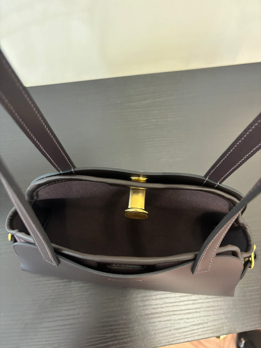 Hermes bag interior view with top opening, dark lining and gold-tone clasp detail.