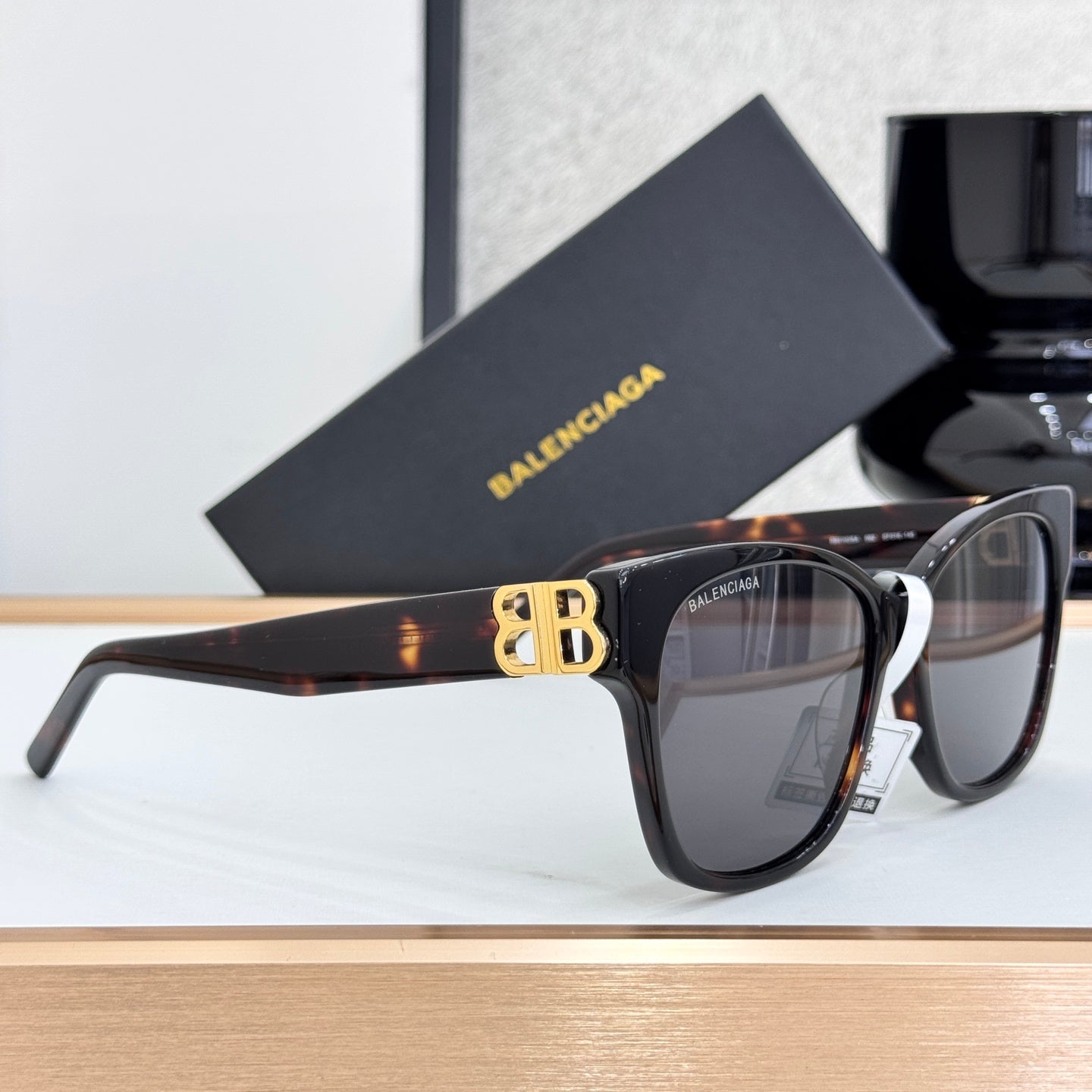 Balenciaga sunglasses with dark lenses, brown tortoiseshell temple, and gold B emblem