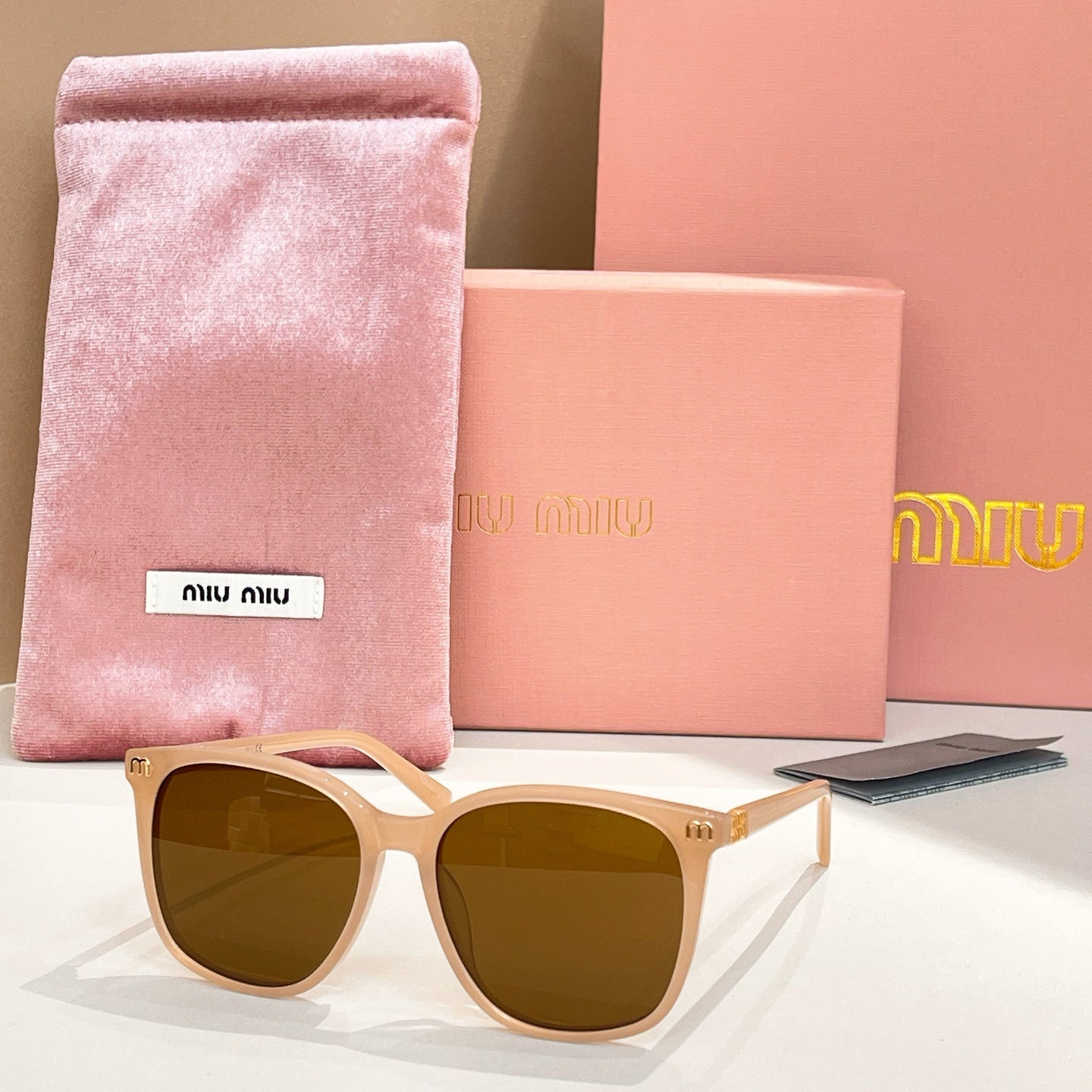 MiuMiu sunglasses with white frame and dark brown lenses, with pink storage pouch