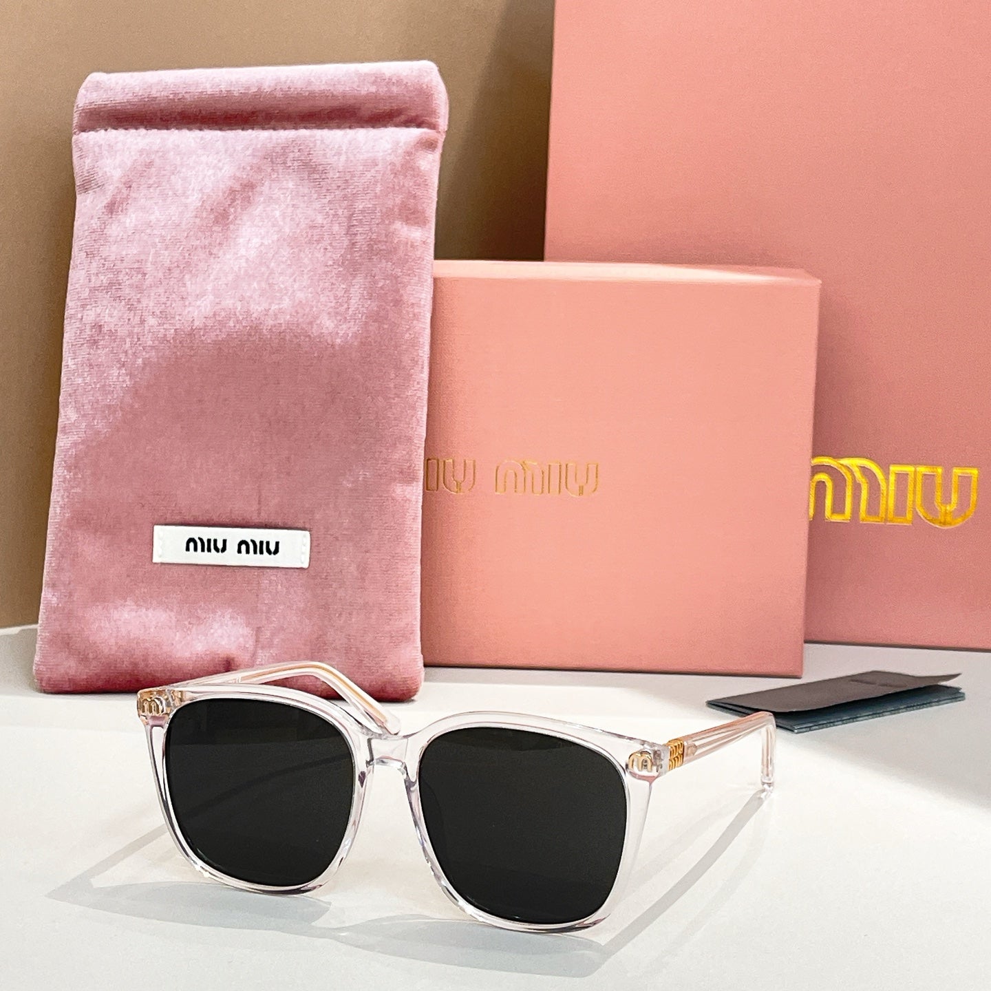 MiuMiu sunglasses with silver frame and black lenses, with pink storage pouch