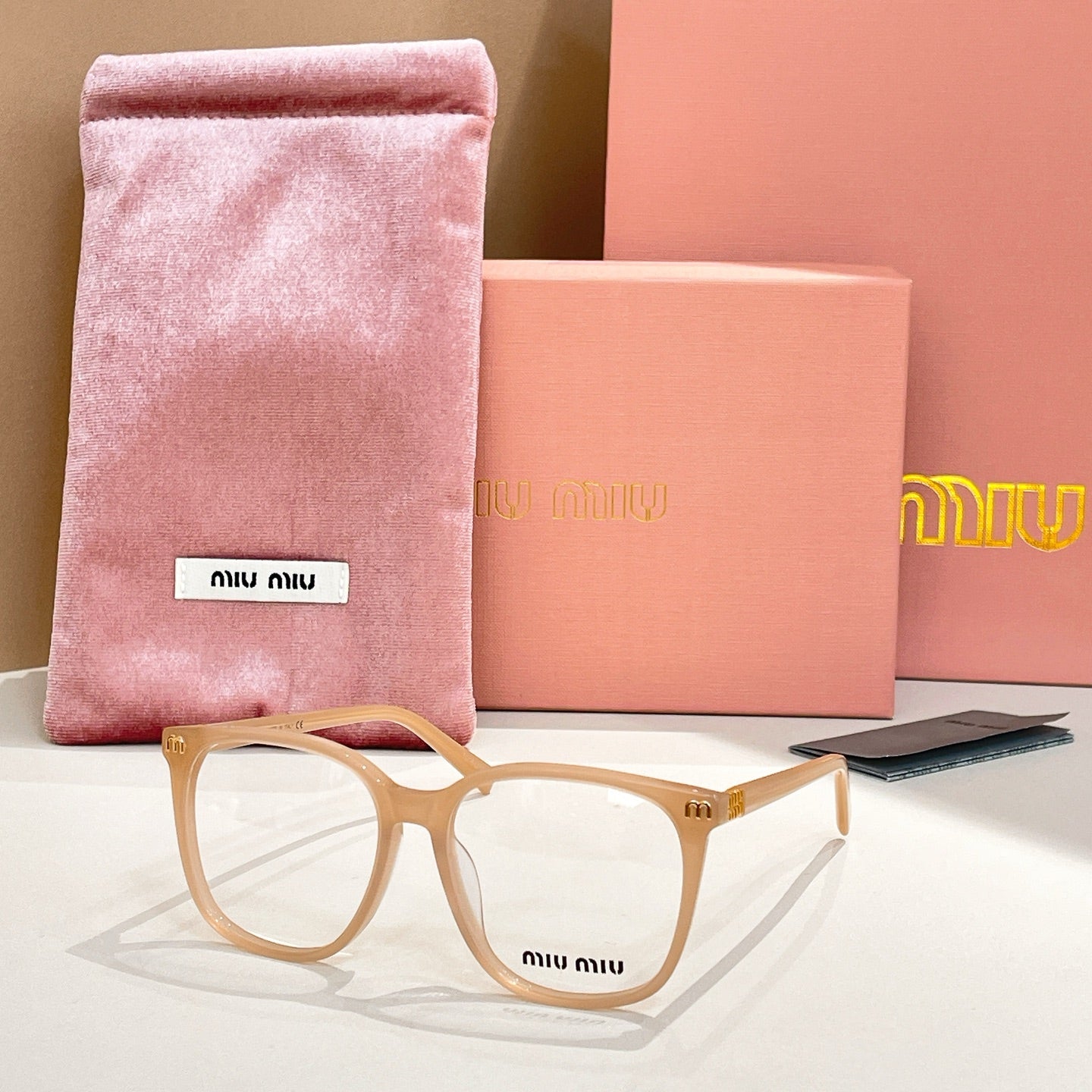MiuMiu eyeglasses with tan frame and clear lenses, with pink storage pouch
