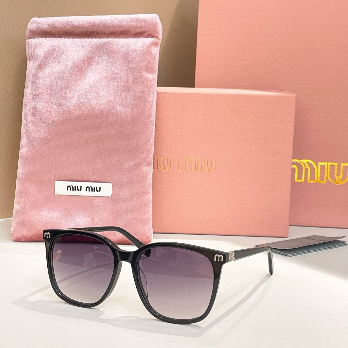MiuMiu sunglasses with black frame and dark lenses, with pink storage pouch