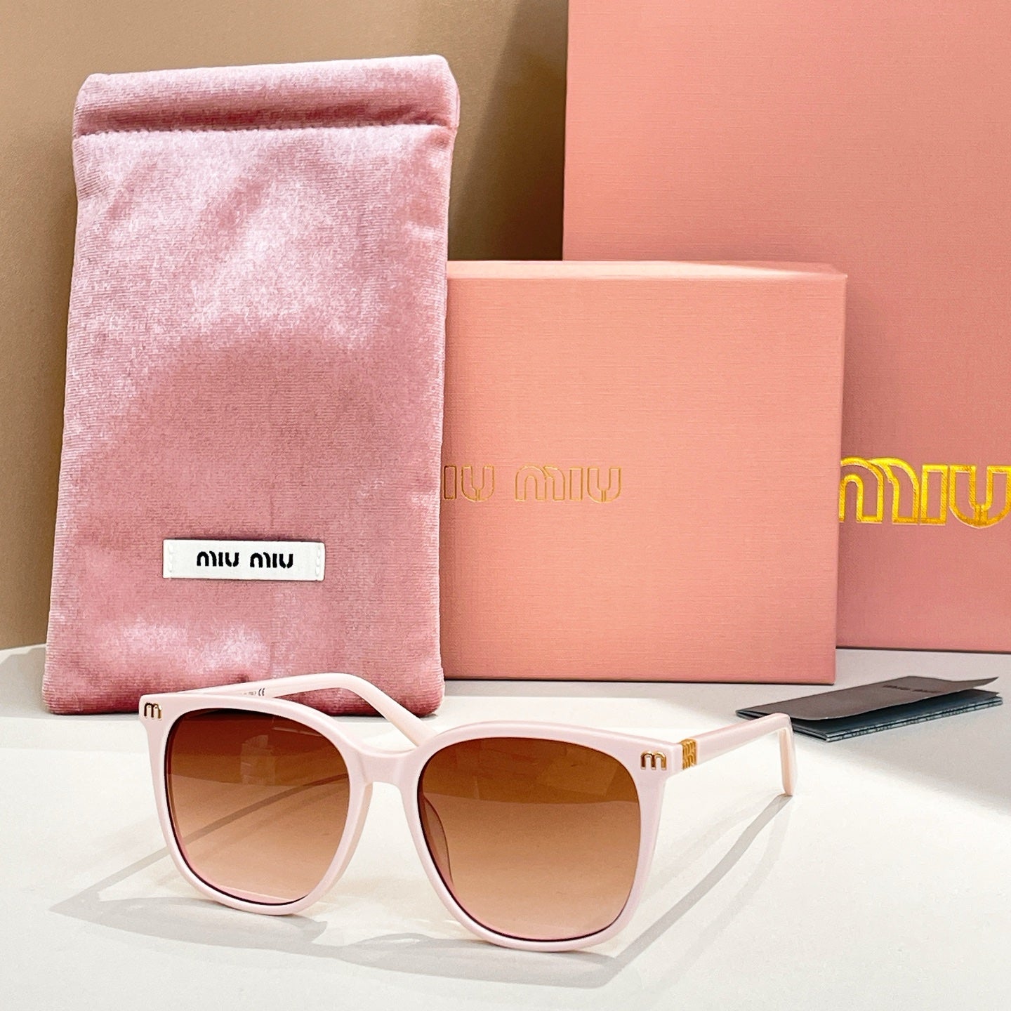 MiuMiu sunglasses with white frame and brown lenses, with pink storage pouch