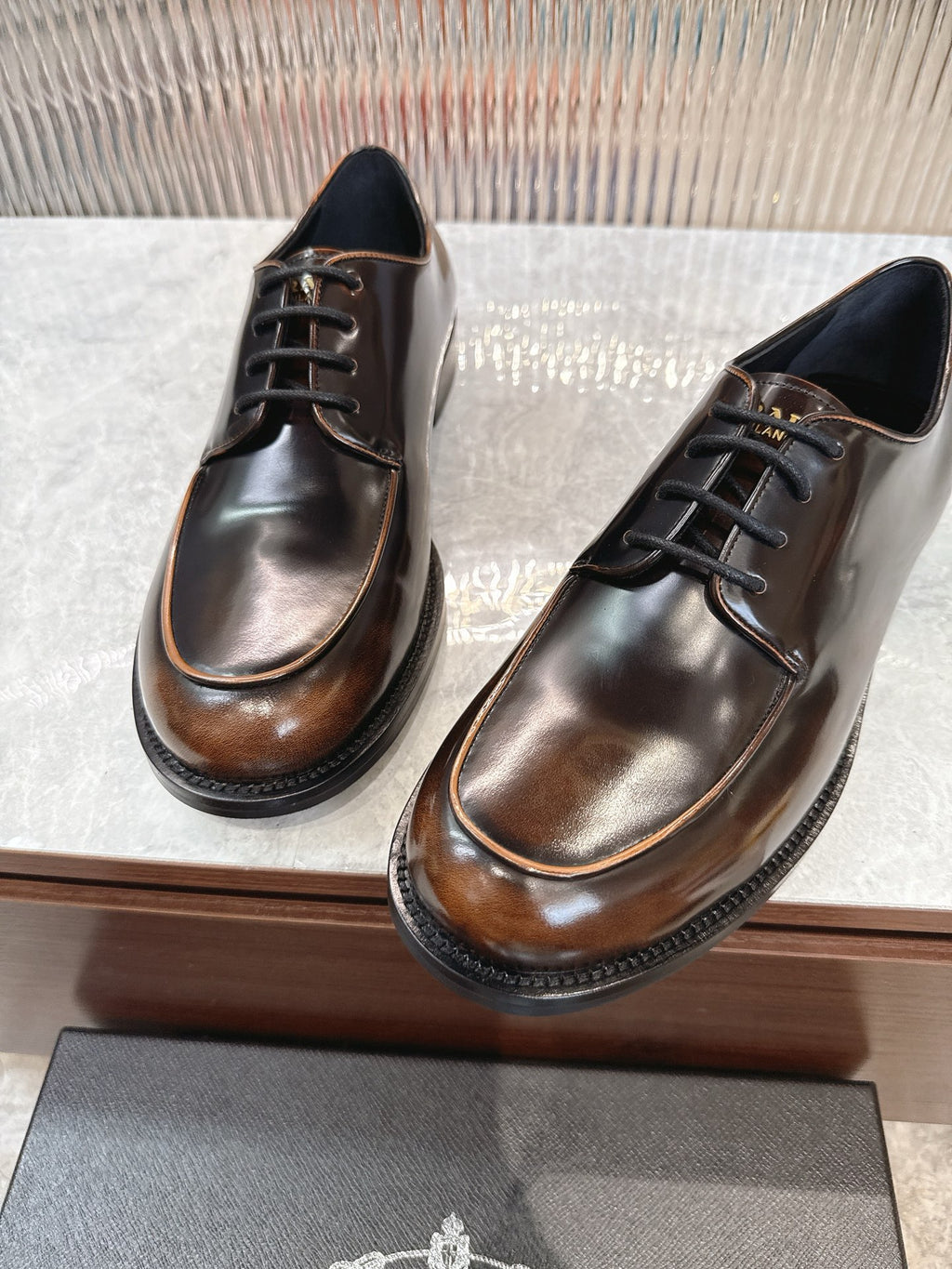 Lace-up leather shoes by Prada, polished dark brown with black laces and stitching detail