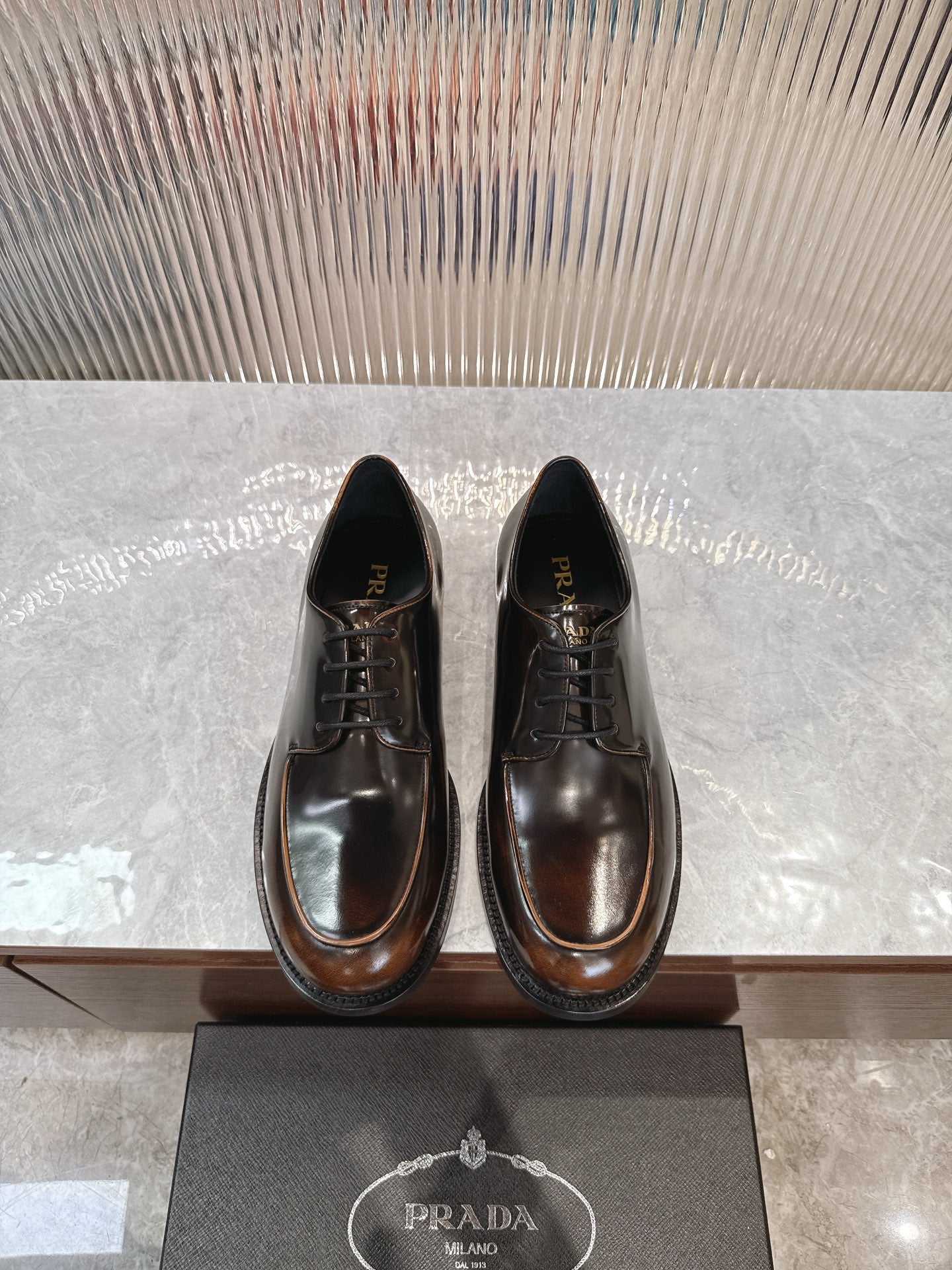 Lace-up leather shoes by Prada, dark brown with black laces and glossy finish