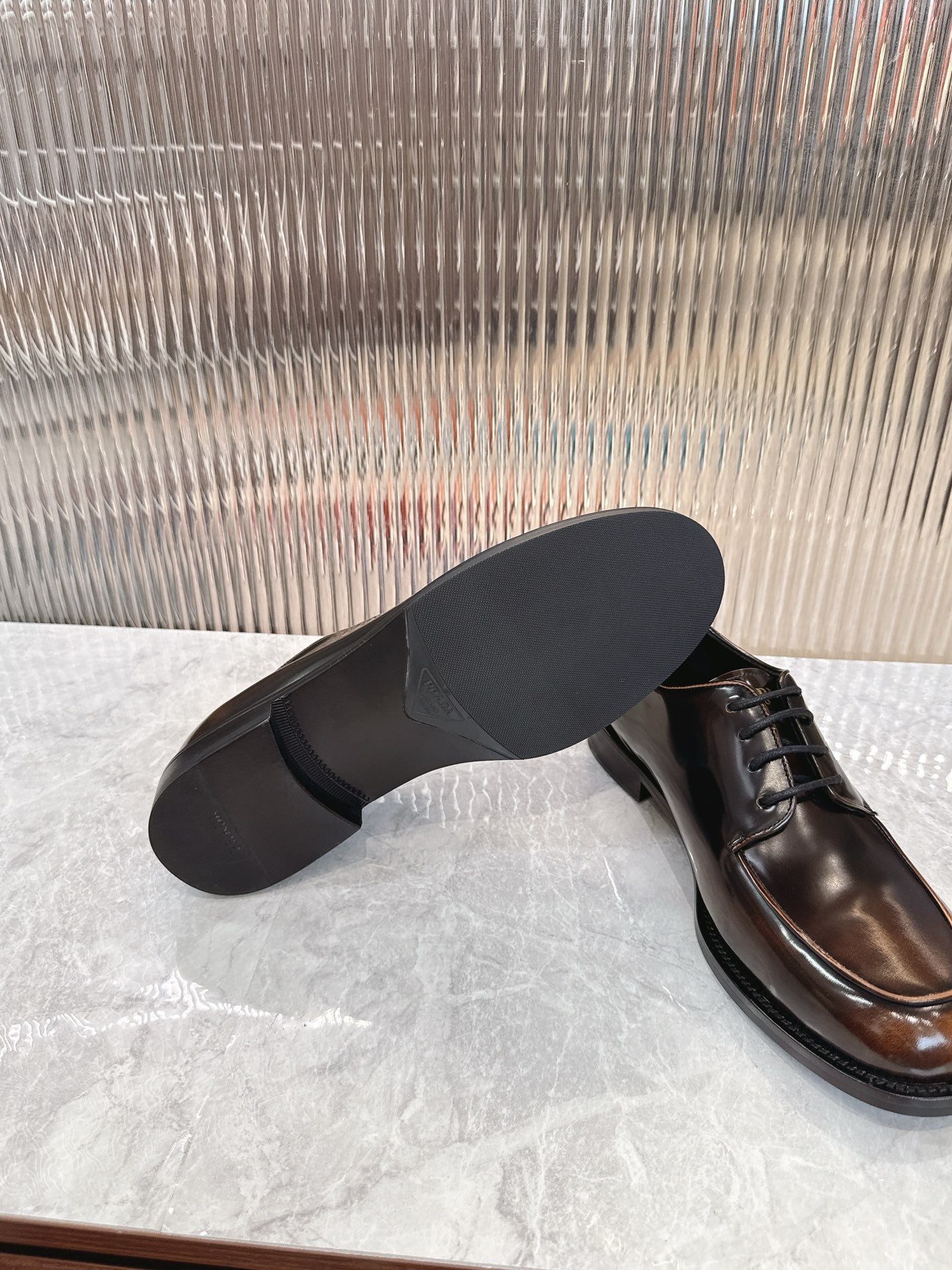 Lace-up leather shoes by Prada, dark brown upper with black sole and low profile heel