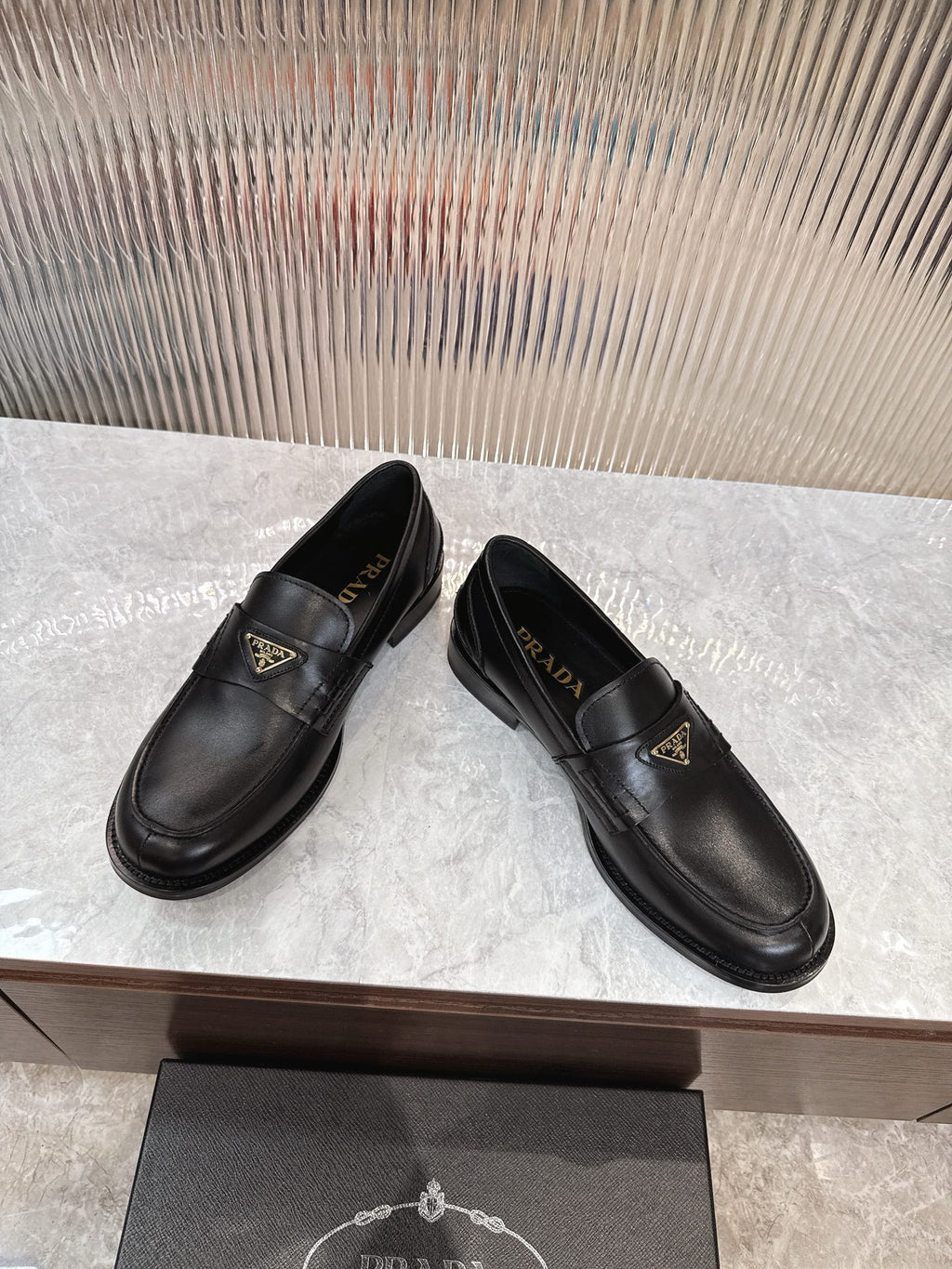 Prada black leather slip-on loafers with gold triangular logo plaque, side view