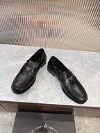 Prada black leather slip-on loafers with gold triangular logo plaque, side view