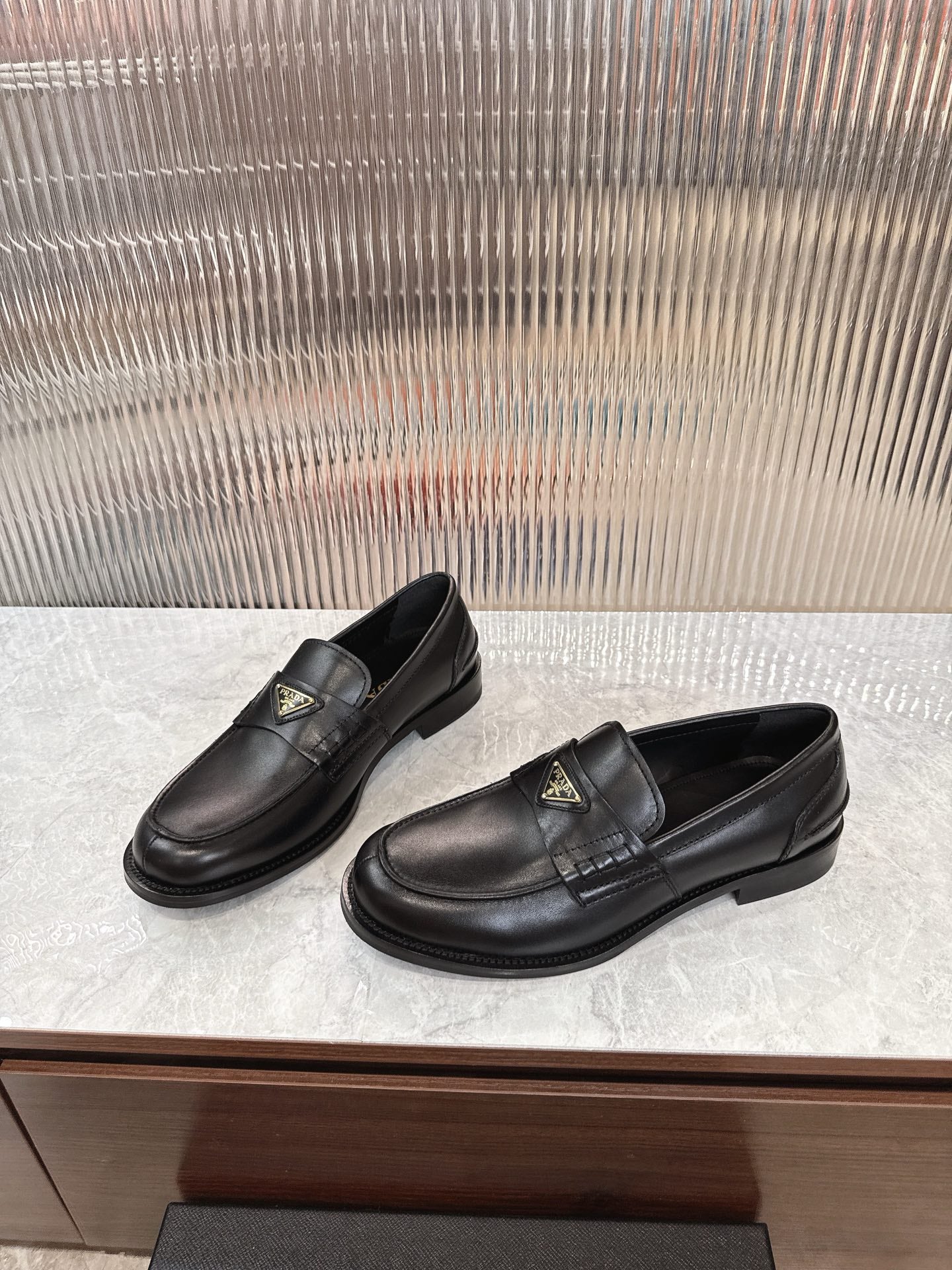 Pair of Prada black leather loafers with gold triangular logo on the vamp