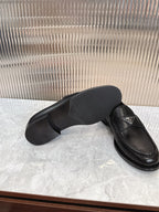 Black leather loafer showing outsole with Prada logo on upper