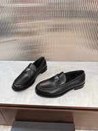 Black leather loafers with low stacked heel and Prada emblem, angled view