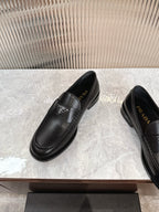 Black leather slip-on loafers with triangular logo on the vamp and stitched apron toe.