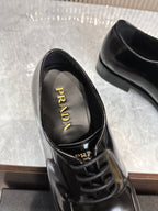 Prada unisex lace-up shoes, glossy black leather, "PRADA" logo on insole.