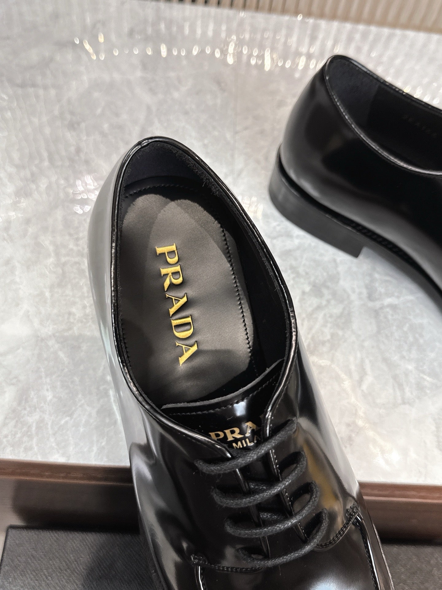 Prada unisex lace-up shoes, glossy black leather, "PRADA" logo on insole.
