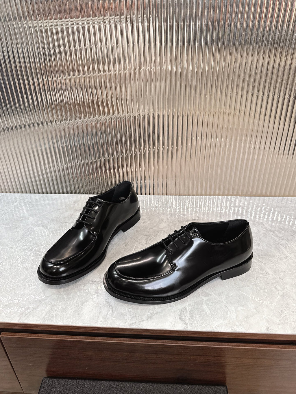 Prada unisex lace-up dress shoes, glossy black leather, front and side angles.