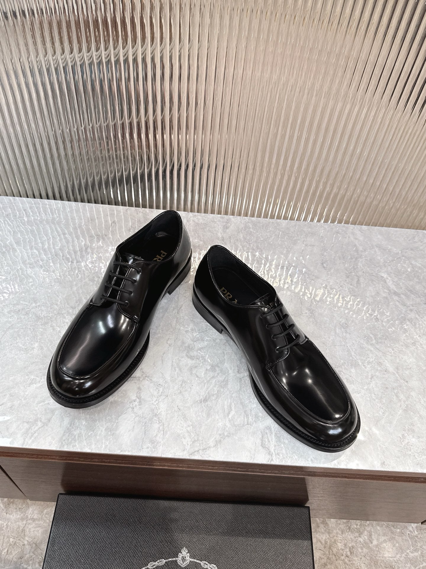 Prada unisex lace-up dress shoes, glossy black leather, low-profile sole.