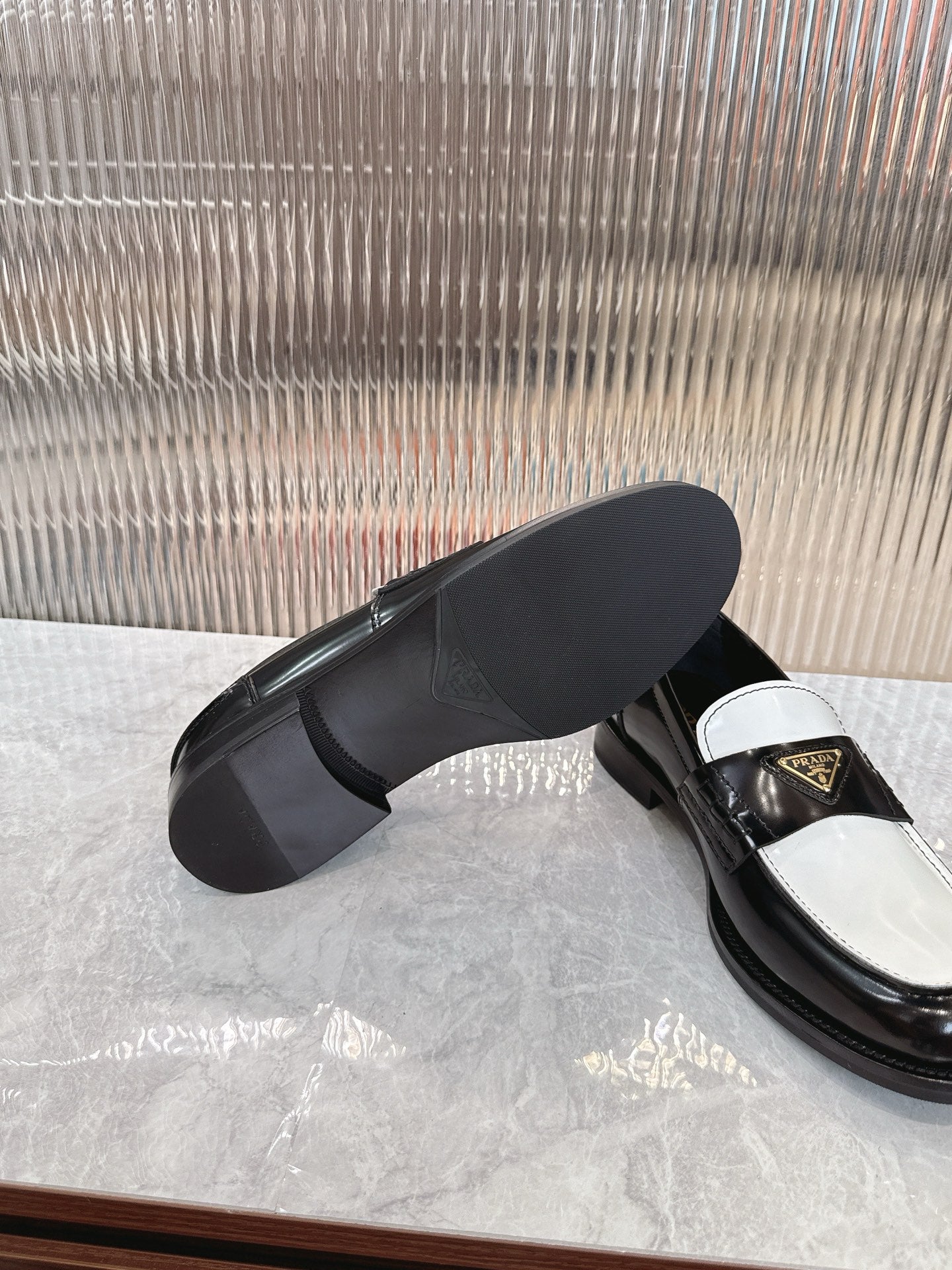 Prada unisex loafers, black leather side view with white strap and gold logo