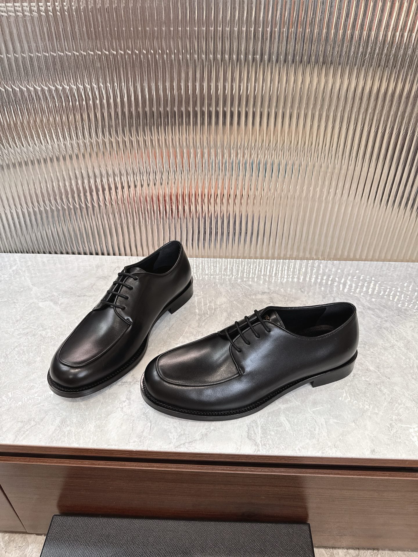 Black lace-up leather shoes with low heel, side view on display