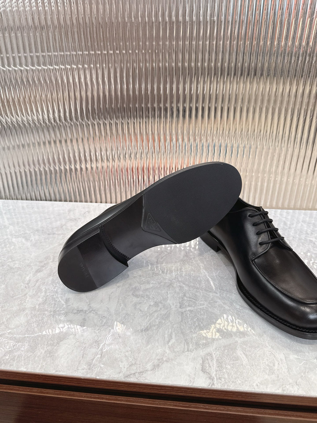 Black leather lace-up shoes showing outsole underside and rounded toe