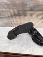 Black loafers shown from above with Prada crest on strap, top view.