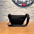 Men's messenger bag in black with adjustable shoulder strap and rounded silhouette.