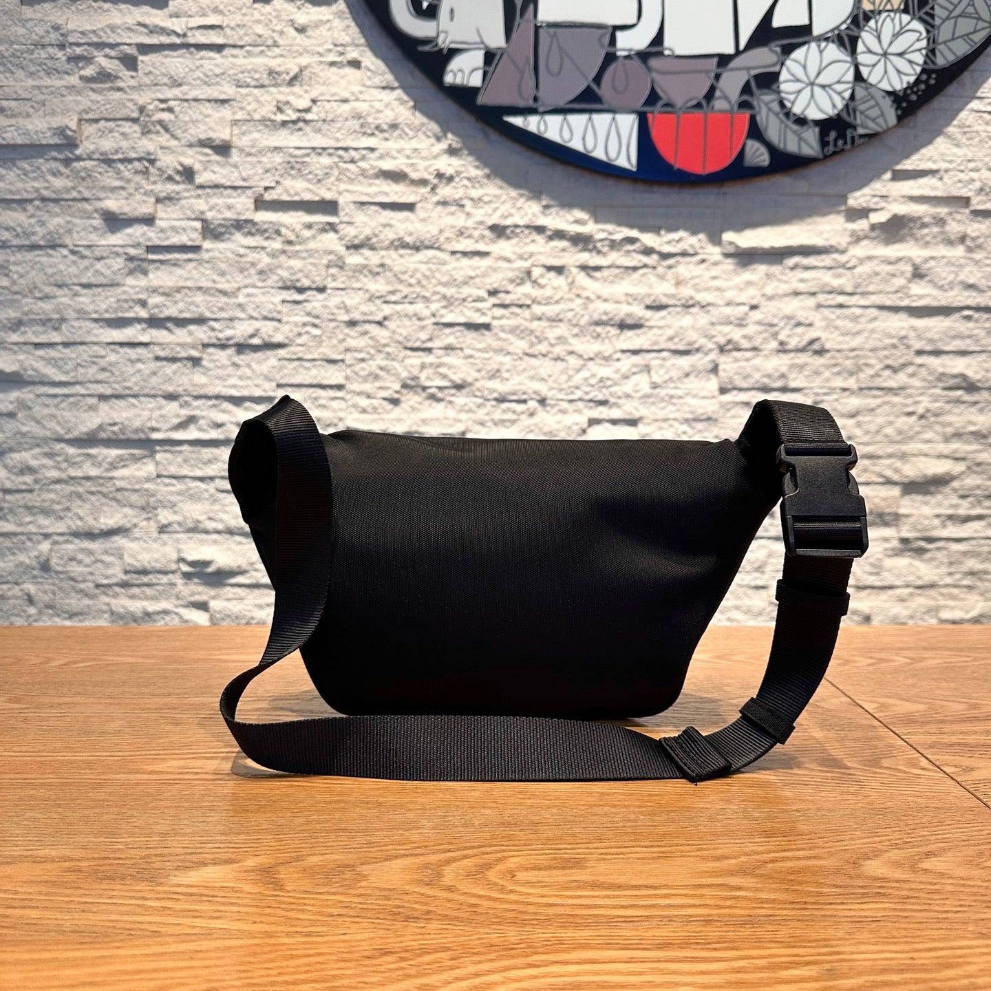 Men's messenger bag in black with adjustable shoulder strap and rounded silhouette.