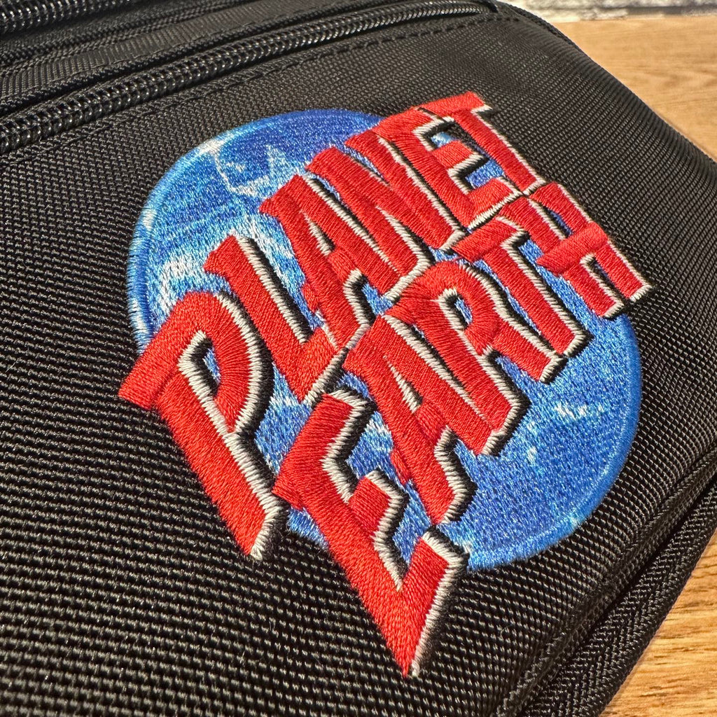 Black bag fabric with Planet Earth embroidered logo patch detail.