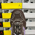 Brown leather sneaker toe with lace eyelets and purple emblem detail.