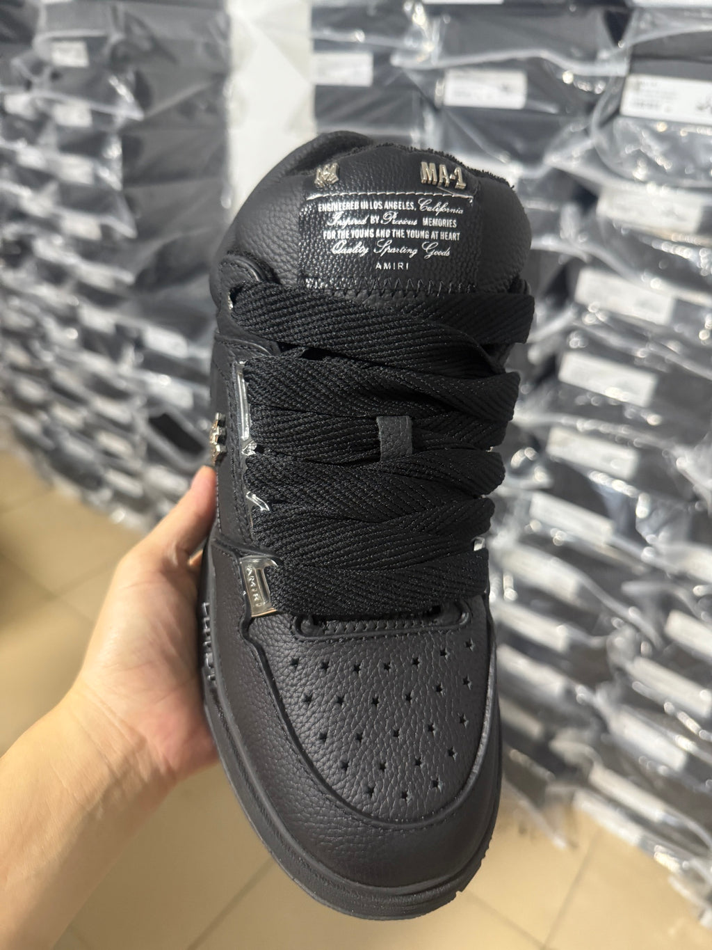 Black Amiri sneakers back view, laces tied with logo text on the tongue