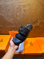 Hermes leather slide sandals on boxes, dark navy two-strap design with buckle hardware