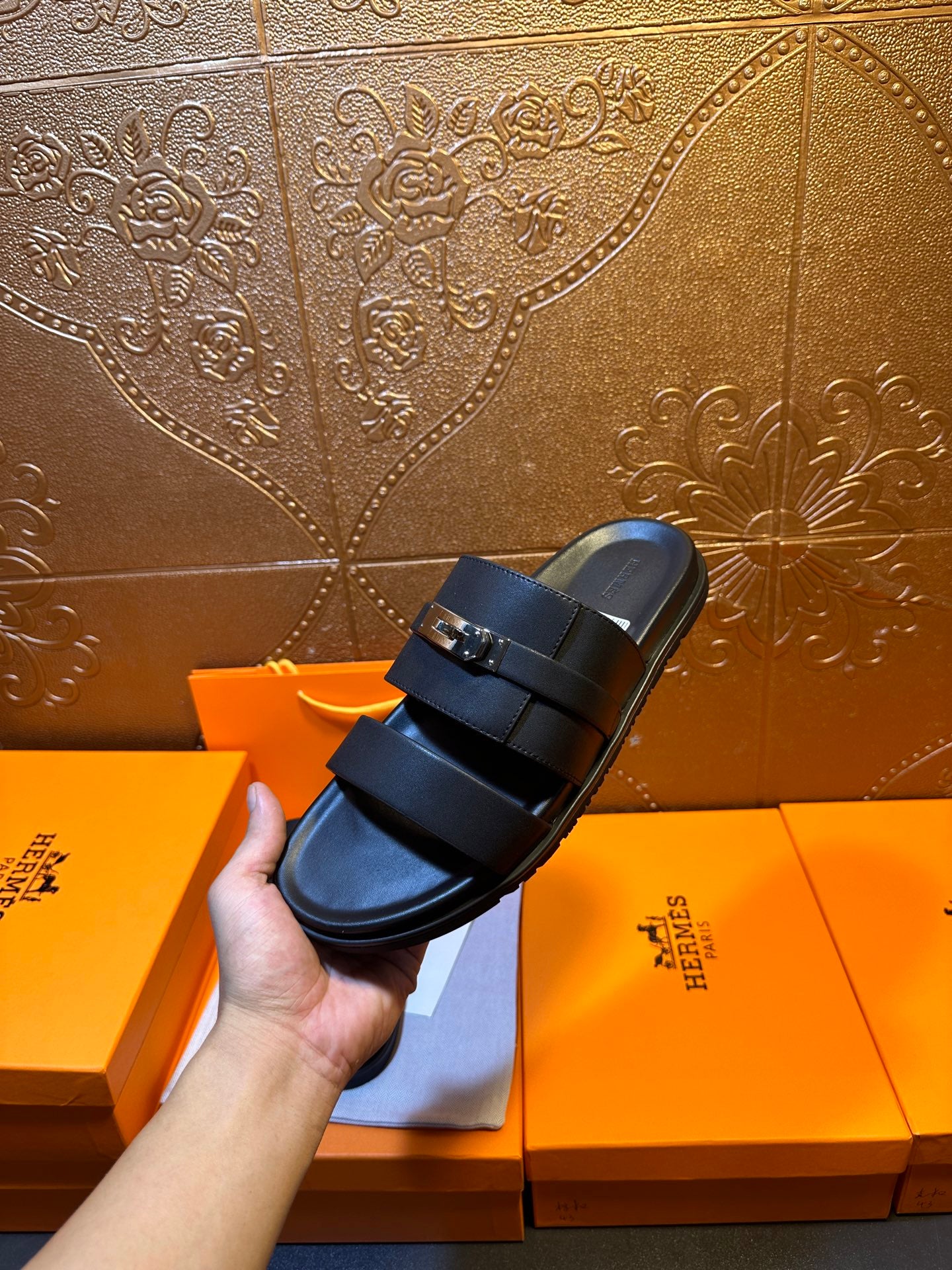 Hermes leather slide sandals on boxes, dark navy two-strap design with buckle hardware