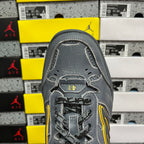 Grey sneaker toe and lace area with yellow trim accents and stitched overlay details.