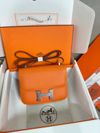 Orange leather flap bag with front H clasp, shown in orange gift box