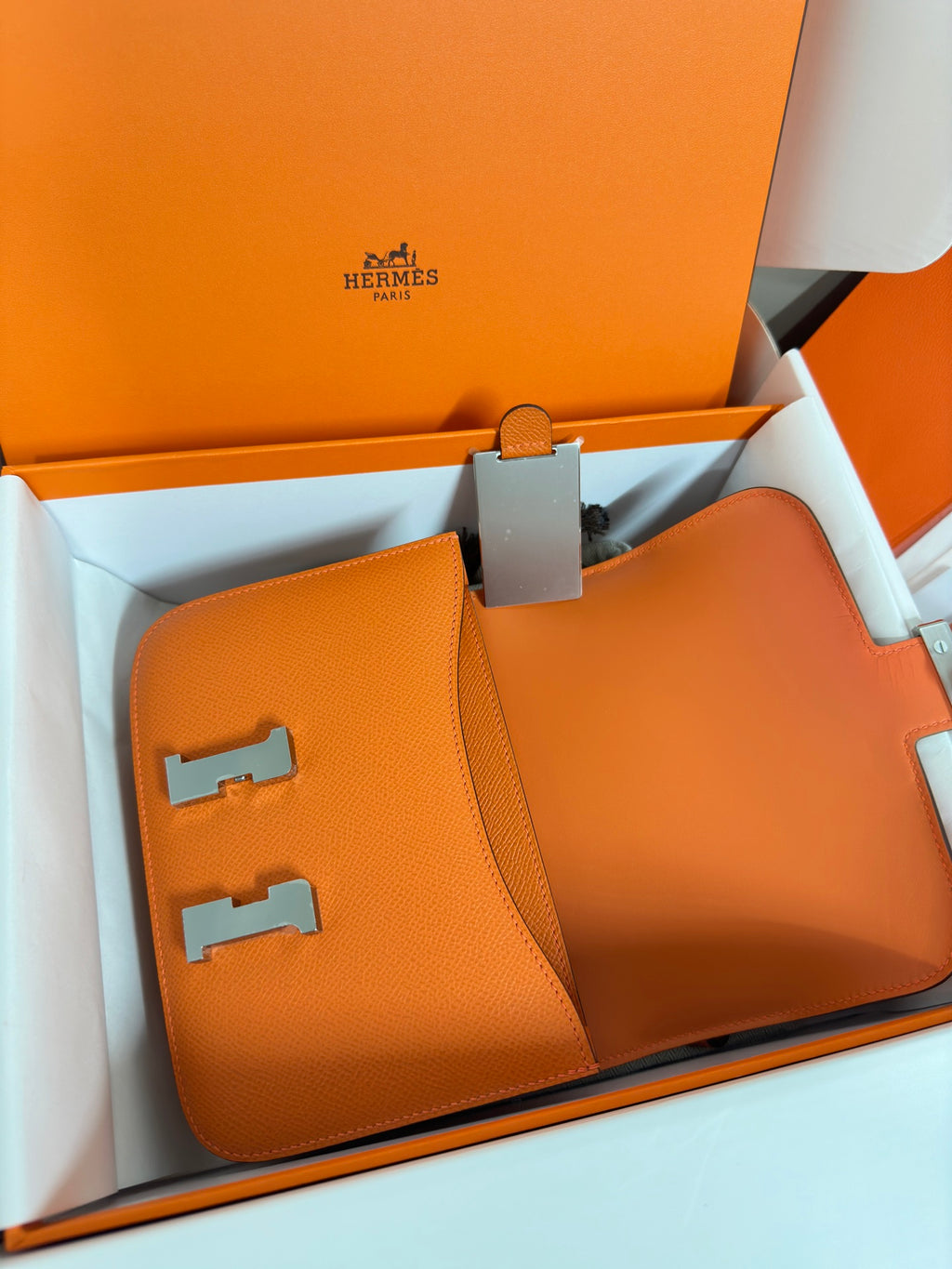 Orange leather mini bag close-up, showing front H clasp and flap