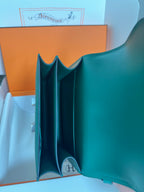 Teal-green leather handbag interior view with H logo patch at base