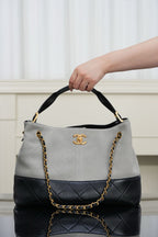 Chanel bag in quilted two-tone gray and black, gold chain shoulder strap, top handle.