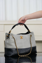 Chanel bag with quilted two-tone gray-and-black panels and gold chain shoulder straps.