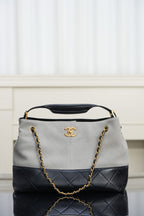 Chanel bag with quilted two-tone design, gold chain shoulder strap, top handle.