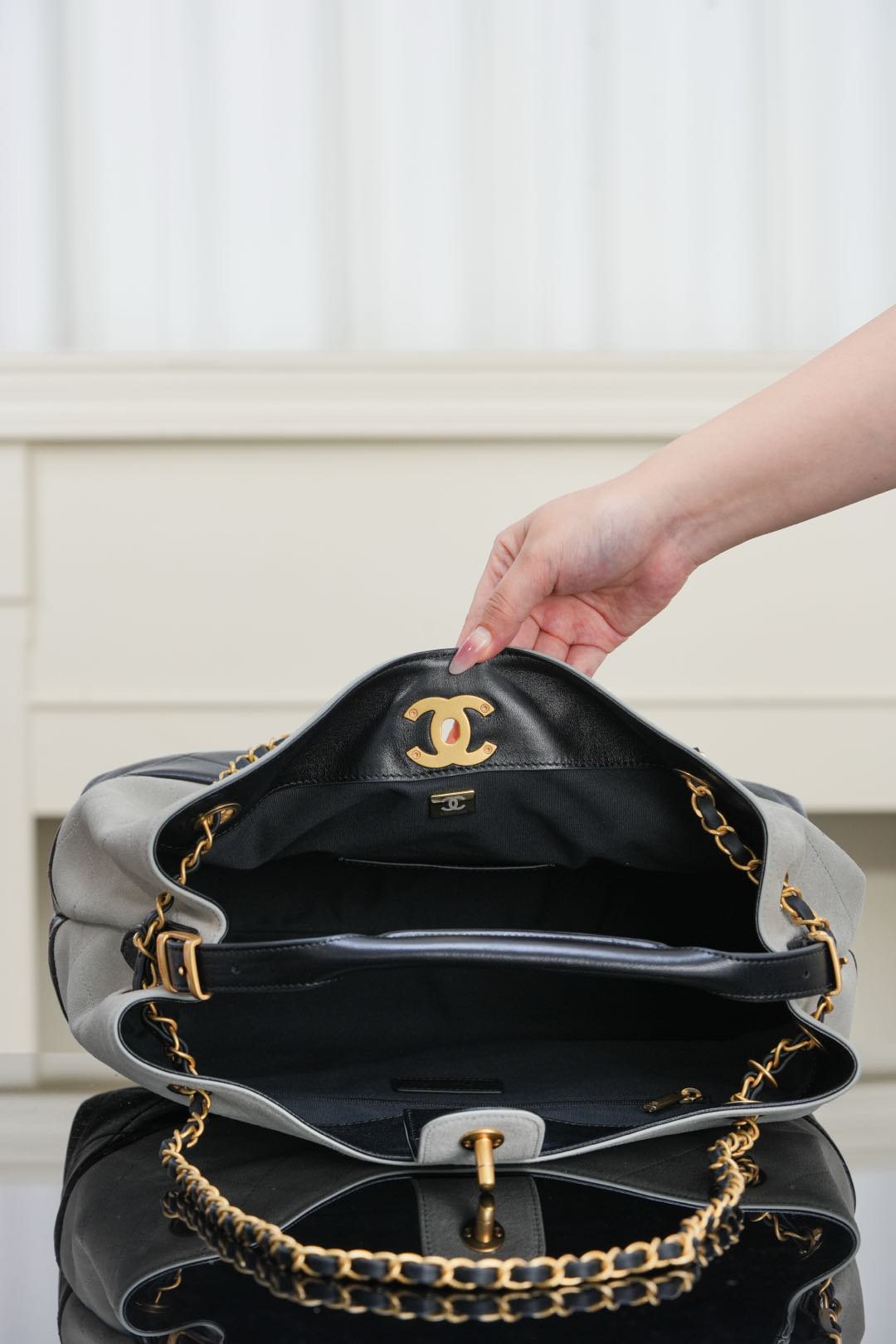 Chanel bag with stacked quilted black and gray panels, gold chain strap, top opening.