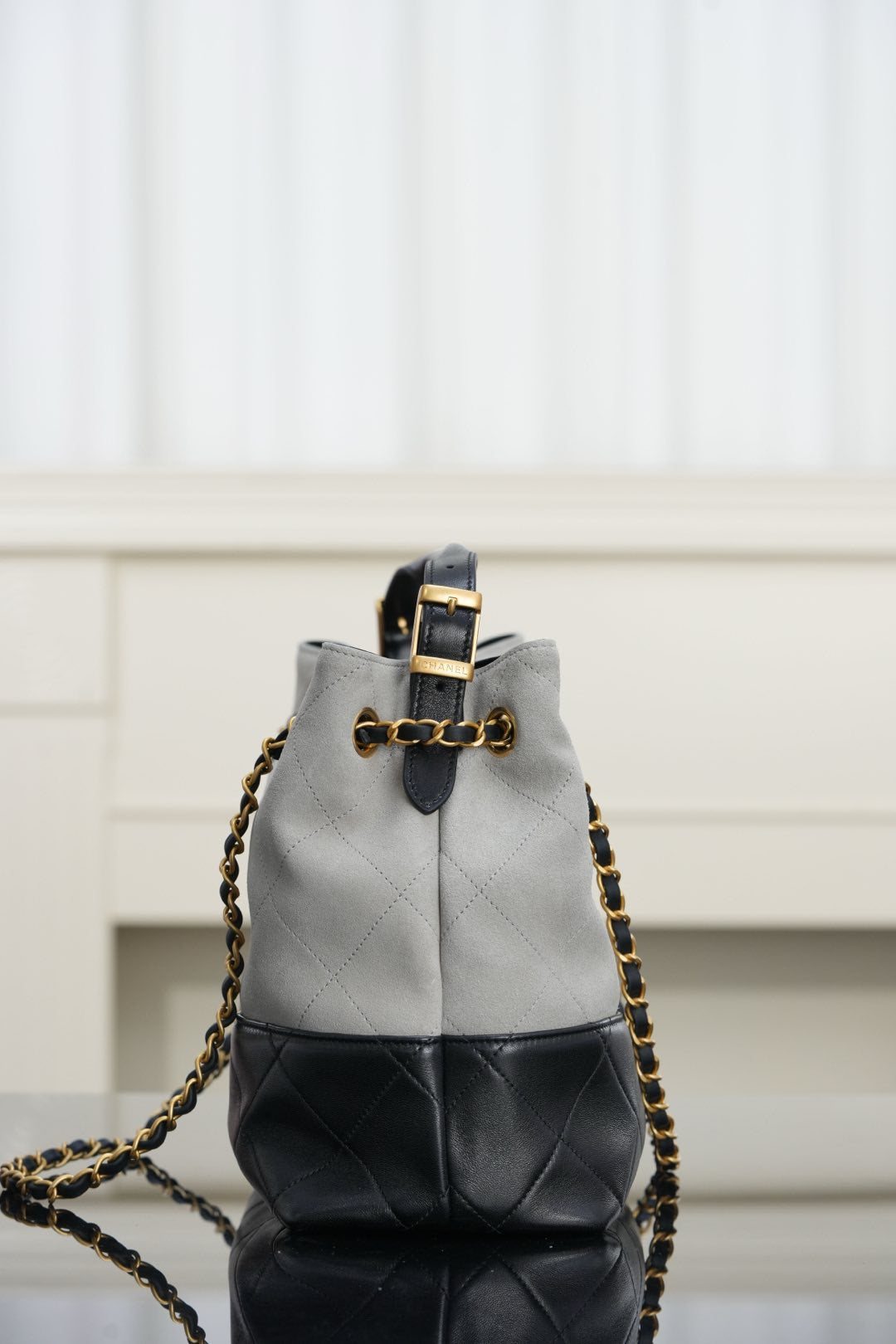 Chanel bag with quilted two-tone gray and black, gold chain strap and top handle.
