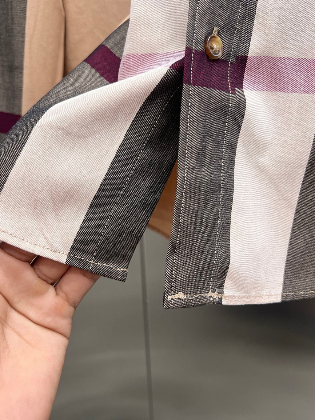 Sleeve cuff close-up on plaid long-sleeve button-up shirt with stitched trim