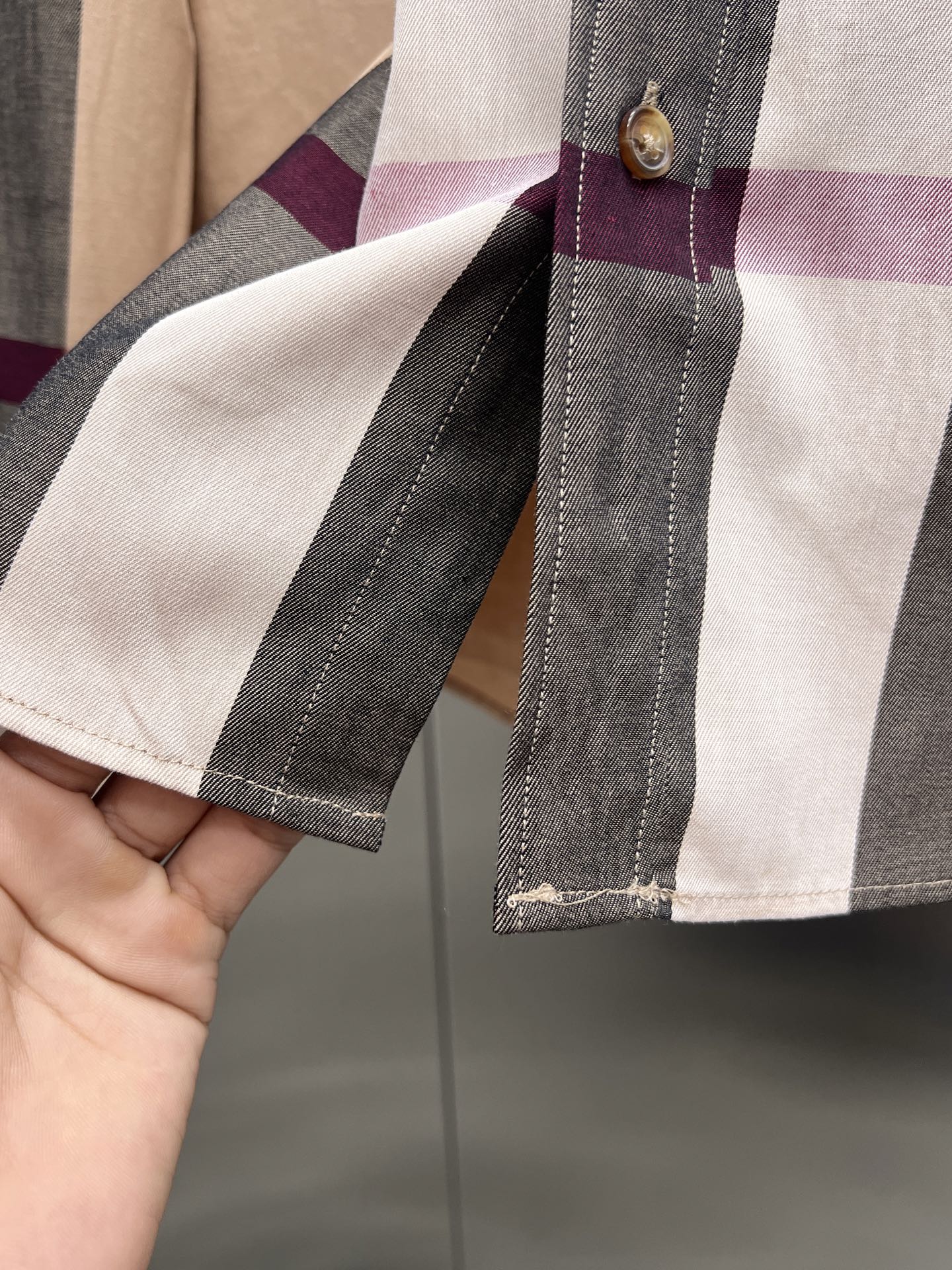Sleeve cuff close-up on plaid long-sleeve button-up shirt with stitched trim