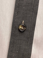 Shirt placket close-up with round metal button and stitched trim in plaid