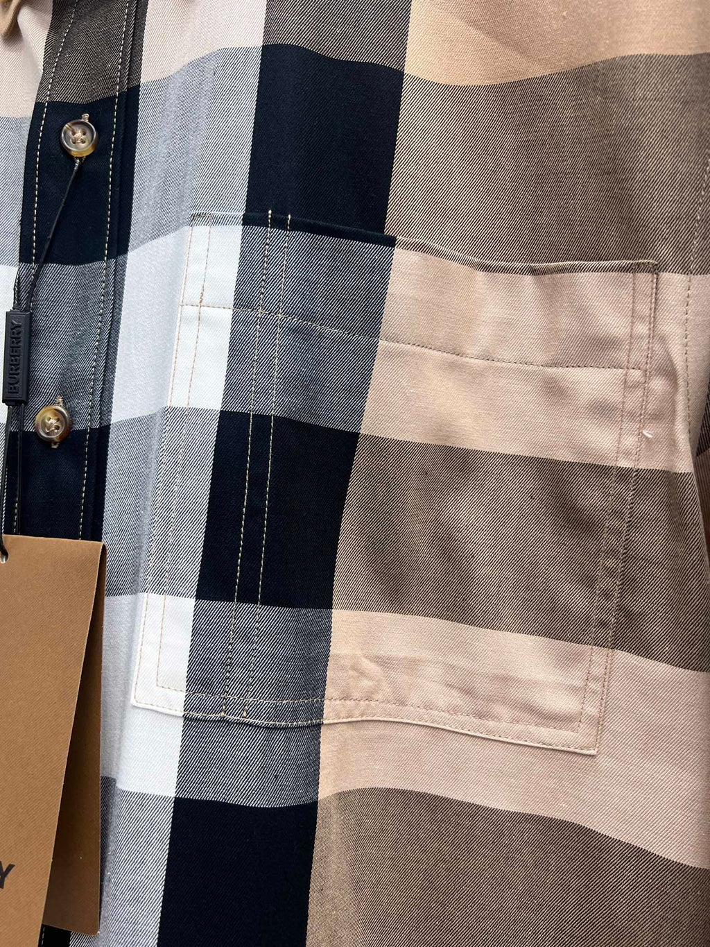 Close-up of long-sleeve shirt pocket and plaid panel; gold-tone button