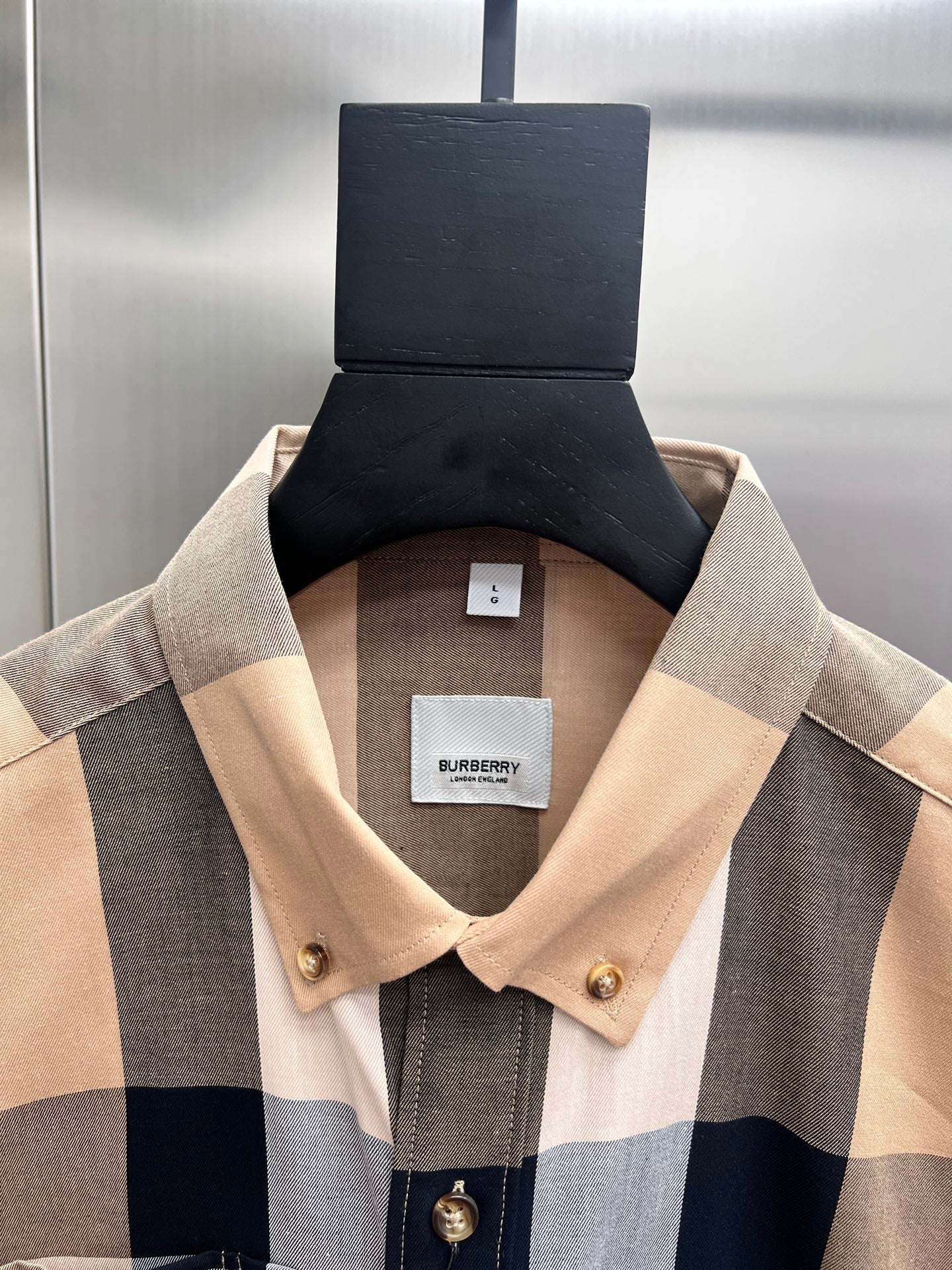 Long-sleeve button-up shirt neckline with beige and navy plaid; buttoned placket