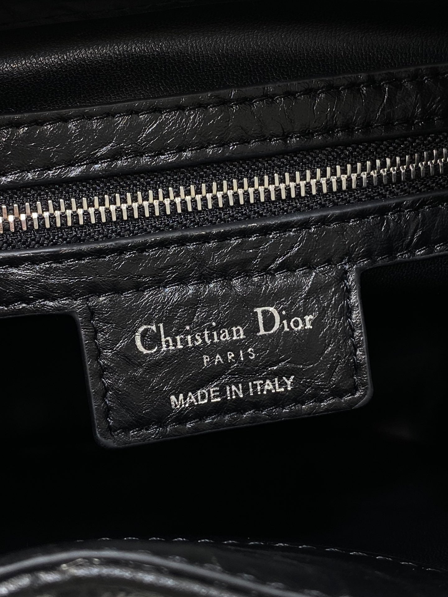 Dior black leather bag tag reading Christian Dior Paris and Made in Italy