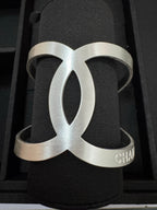 Chanel silver-tone CC cuff bracelet on dark fabric