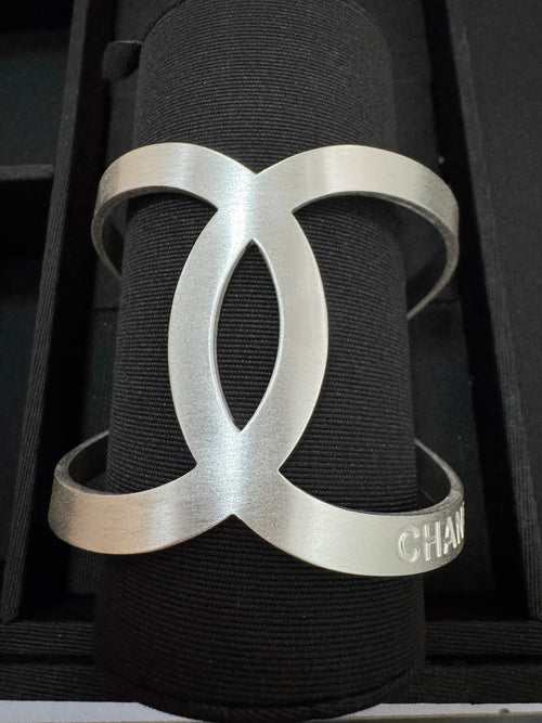 Chanel silver-tone CC cuff bracelet on dark fabric